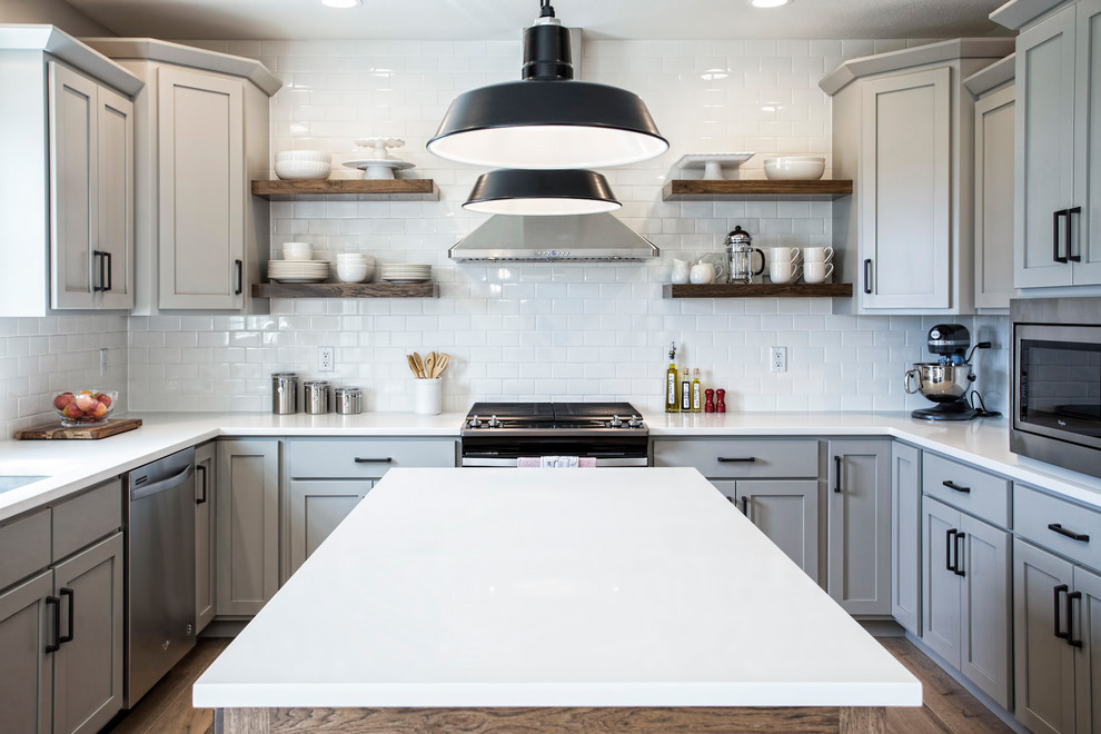 Inredning av ett klassiskt mellanstort vit vitt kök, med en undermonterad diskho, skåp i shakerstil, grå skåp, bänkskiva i kvarts, vitt stänkskydd, stänkskydd i tunnelbanekakel, rostfria vitvaror, ljust trägolv, en köksö och beiget golv