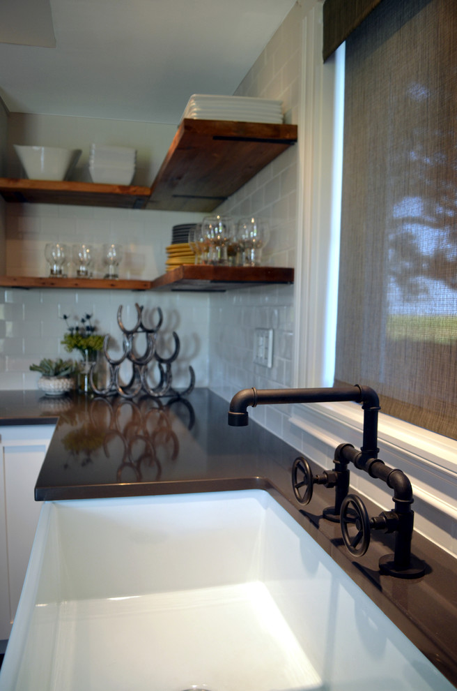 Foto på ett industriellt kök, med en rustik diskho, skåp i shakerstil, vita skåp, bänkskiva i kvarts, vitt stänkskydd, stänkskydd i tunnelbanekakel, mellanmörkt trägolv och en köksö