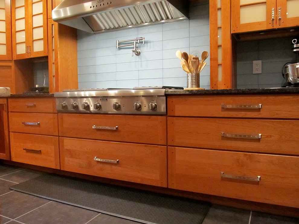 Exempel på ett avskilt, mellanstort industriellt u-kök, med en undermonterad diskho, släta luckor, skåp i mellenmörkt trä, granitbänkskiva, blått stänkskydd, stänkskydd i glaskakel, rostfria vitvaror, klinkergolv i porslin, en köksö och grått golv