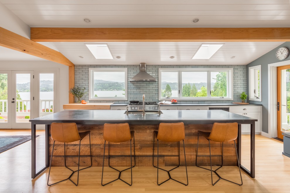 シアトルにあるラスティックスタイルのおしゃれなアイランドキッチン (白いキャビネット、青いキッチンパネル、レンガのキッチンパネル、無垢フローリング) の写真