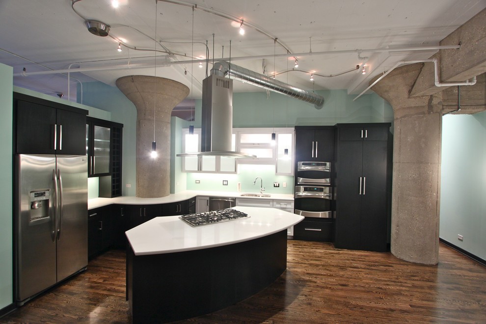 Idee per una cucina industriale con ante di vetro, ante nere, elettrodomestici in acciaio inossidabile, lavello sottopiano, top in quarzo composito e pavimento in legno massello medio