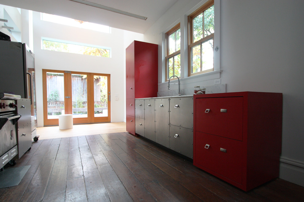 Urban galley open plan kitchen in Portland with flat-panel cabinets, red cabinets, white splashback, stainless steel appliances, a submerged sink and medium hardwood flooring.