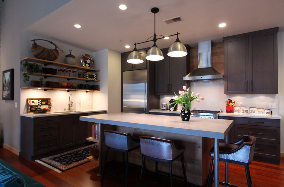 Esempio di una cucina industriale di medie dimensioni con ante lisce, ante in legno chiaro, top in cemento, elettrodomestici in acciaio inossidabile, parquet scuro, pavimento rosso e top grigio