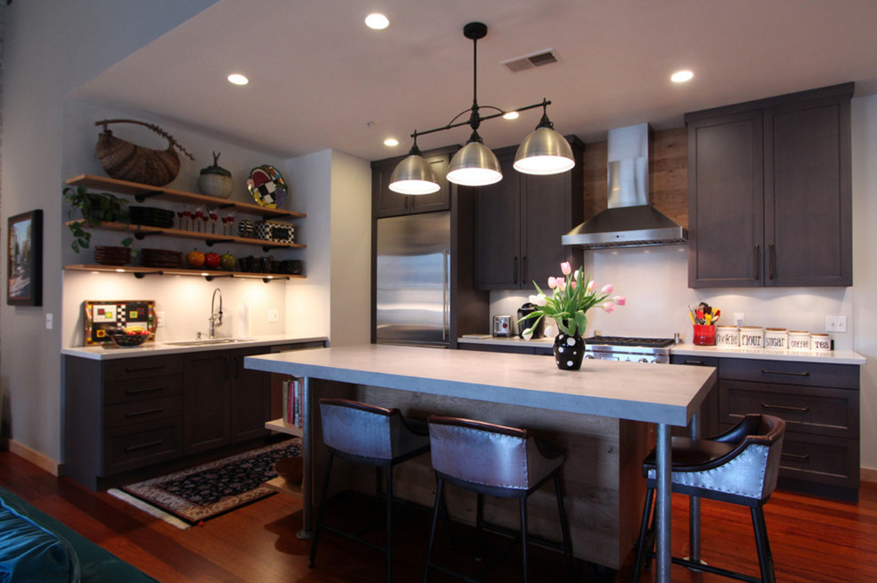 Inspiration for a mid-sized industrial l-shaped dark wood floor and red floor kitchen remodel in Other with flat-panel cabinets, light wood cabinets, concrete countertops, stainless steel appliances, an island and gray countertops