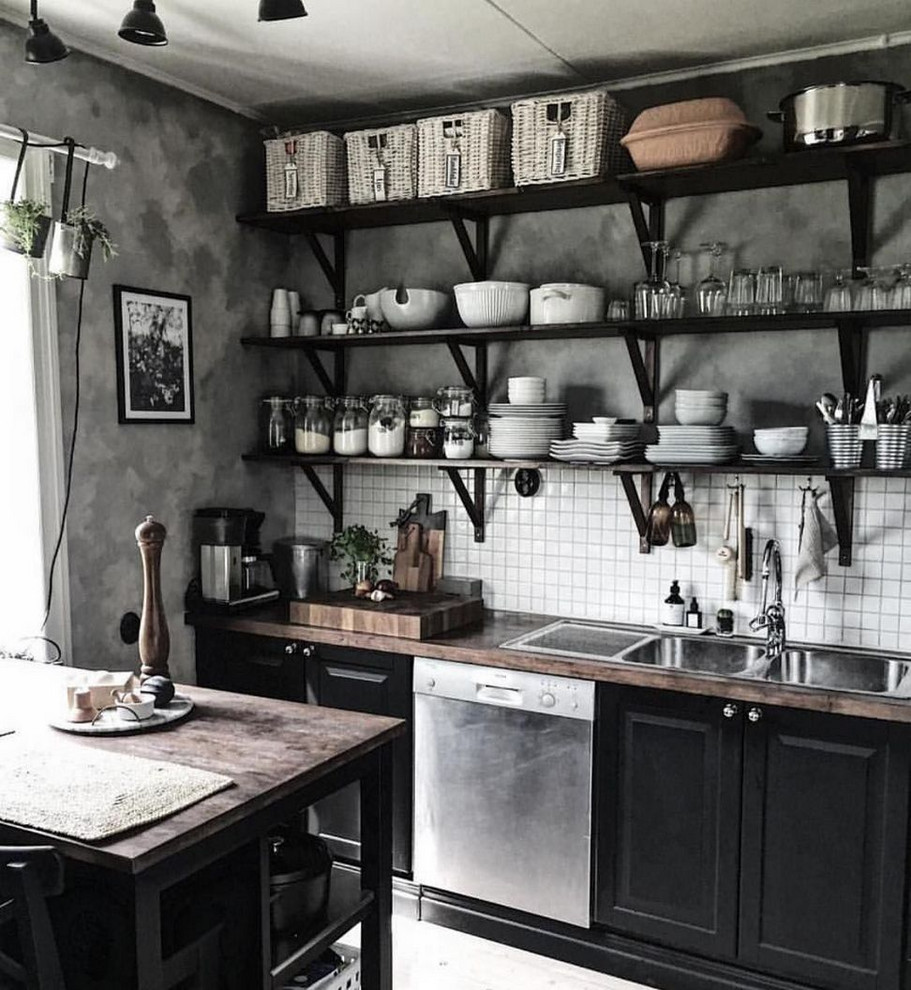 Inspiration for a small industrial single-wall kitchen/diner in Columbus with a built-in sink, raised-panel cabinets, black cabinets, wood worktops, white splashback, ceramic splashback, stainless steel appliances, concrete flooring, an island, grey floors and brown worktops.