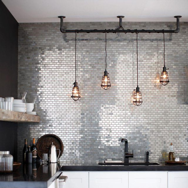 Inspiration for a medium sized industrial l-shaped kitchen/diner in Columbus with a submerged sink, flat-panel cabinets, white cabinets, granite worktops, metallic splashback, metal splashback, stainless steel appliances, medium hardwood flooring, brown floors and black worktops.