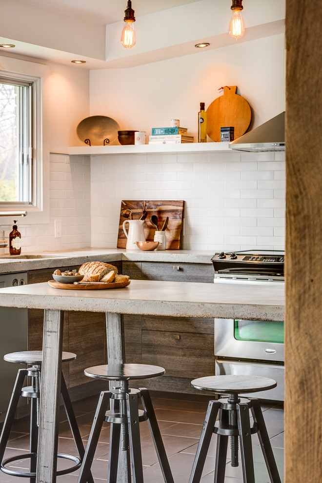 Imagen de cocinas en U urbano de tamaño medio cerrado con fregadero bajoencimera, armarios con paneles lisos, puertas de armario grises, encimera de cemento, salpicadero blanco, salpicadero de azulejos de cerámica, electrodomésticos de acero inoxidable, suelo de baldosas de porcelana y una isla