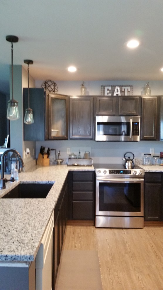This is an example of a small industrial u-shaped kitchen/diner in Milwaukee with a submerged sink, shaker cabinets, black cabinets, granite worktops, white splashback, metro tiled splashback, stainless steel appliances, vinyl flooring and a breakfast bar.
