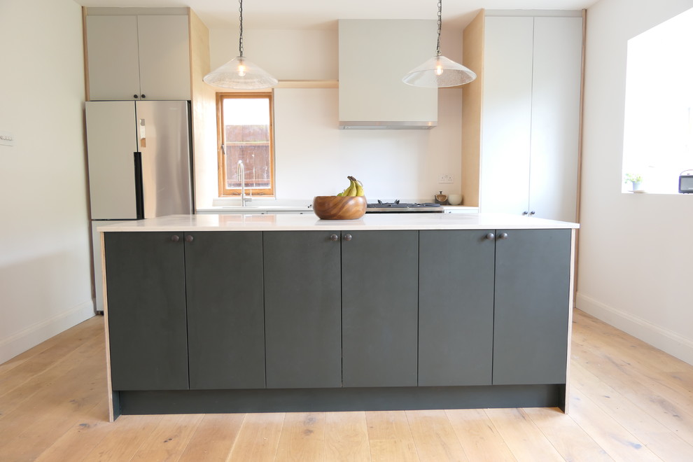 Imagen de cocina lineal industrial de tamaño medio abierta con armarios con paneles lisos, puertas de armario verdes, encimera de cuarzo compacto y una isla