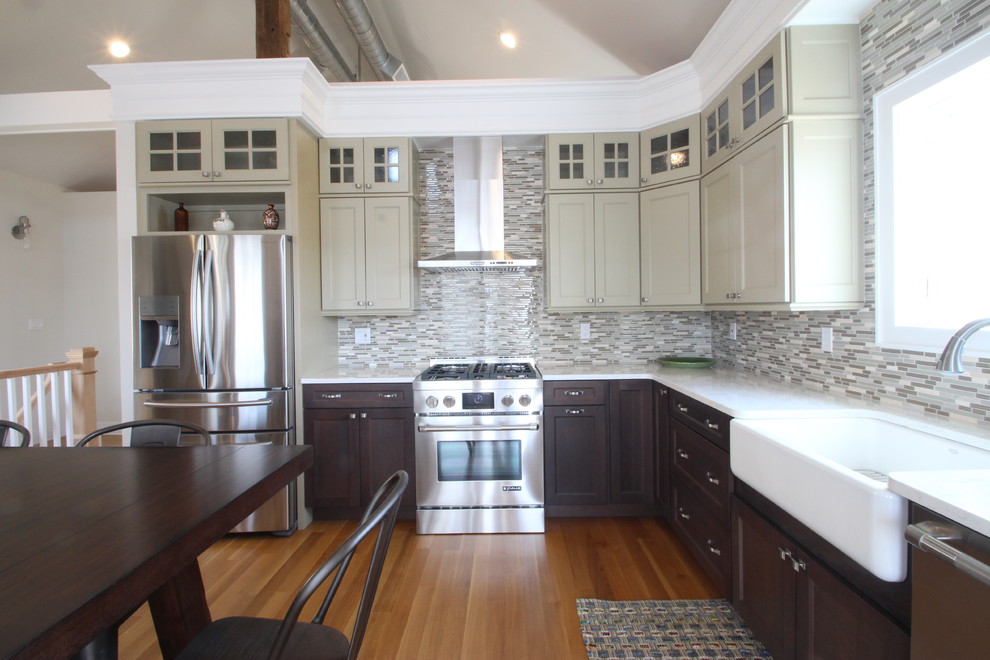 Example of a mid-sized urban l-shaped light wood floor eat-in kitchen design in New York with a farmhouse sink, shaker cabinets, green cabinets, quartz countertops, multicolored backsplash, glass sheet backsplash, white appliances and no island
