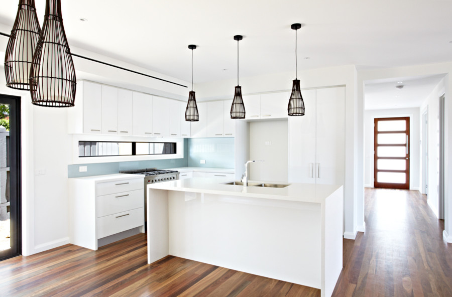 This is an example of a medium sized contemporary l-shaped kitchen/diner in Melbourne with a double-bowl sink, blue splashback, porcelain splashback, plywood flooring, an island and brown floors.