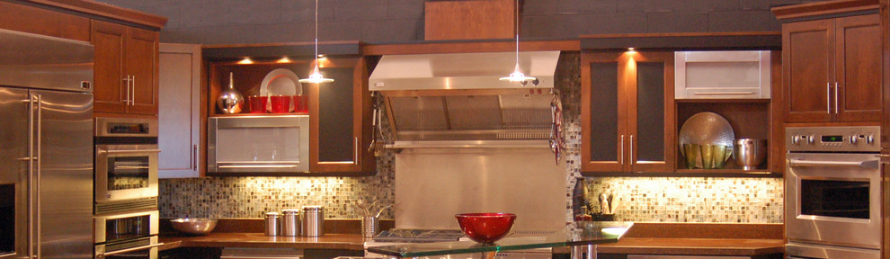 サンルイスオビスポにある広いインダストリアルスタイルのおしゃれなキッチン (シェーカースタイル扉のキャビネット、赤いキャビネット、クオーツストーンカウンター、緑のキッチンパネル、ガラスタイルのキッチンパネル、シルバーの調理設備、無垢フローリング) の写真