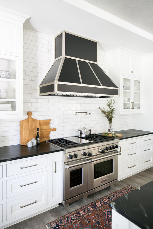 White Cabinets black countertops and Black Range Hood with white subway tile
