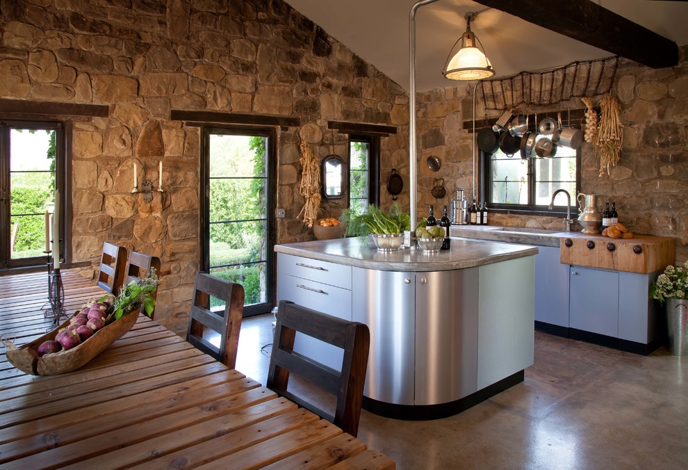 Inredning av ett lantligt litet linjärt kök med öppen planlösning, med en integrerad diskho, släta luckor, skåp i rostfritt stål, bänkskiva i betong, beige stänkskydd, stänkskydd i stenkakel, rostfria vitvaror, betonggolv och en köksö