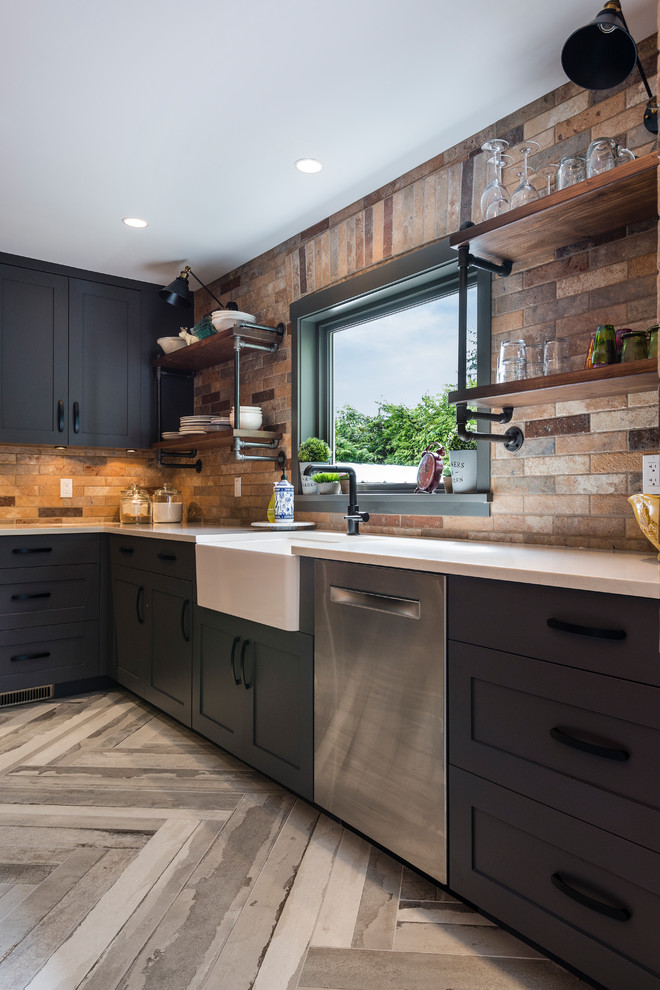 Photo of a large industrial l-shaped open plan kitchen in Vancouver with a submerged sink, shaker cabinets, grey cabinets, engineered stone countertops, brown splashback, brick splashback, stainless steel appliances, porcelain flooring, an island and beige floors.