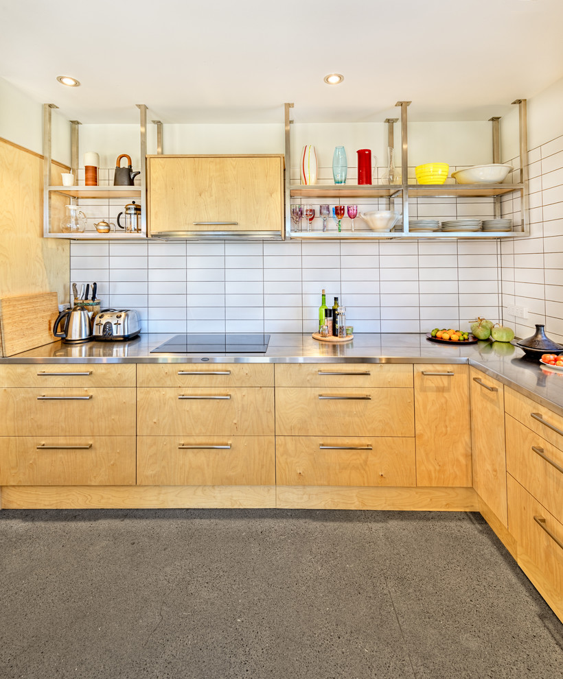 Mid-sized urban l-shaped concrete floor and gray floor eat-in kitchen photo in Auckland with light wood cabinets, stainless steel countertops, white backsplash, stainless steel appliances, an integrated sink, flat-panel cabinets, subway tile backsplash and an island