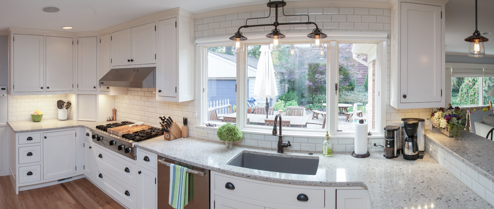Inspiration for a medium sized urban l-shaped open plan kitchen in Grand Rapids with a submerged sink, recessed-panel cabinets, white cabinets, engineered stone countertops, white splashback, ceramic splashback, stainless steel appliances, light hardwood flooring and no island.