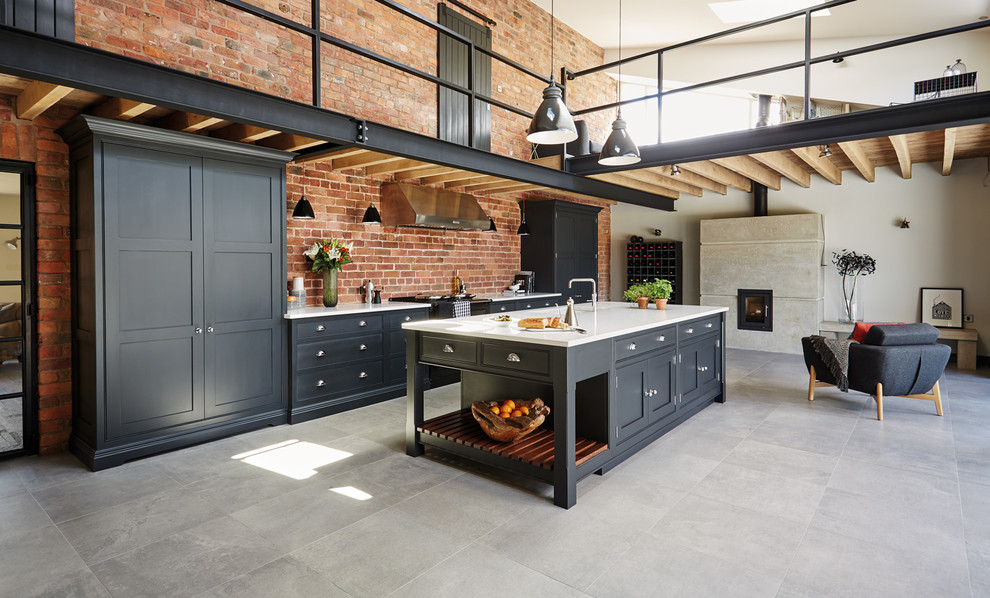 Large industrial open plan kitchen in Manchester with shaker cabinets, black cabinets, quartz worktops, an island and integrated appliances.