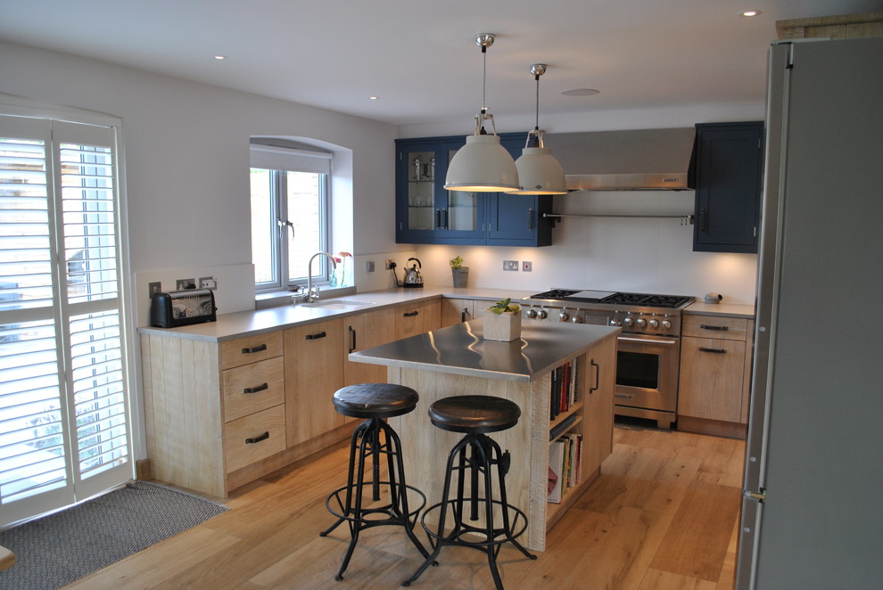 Medium sized urban u-shaped kitchen in Kent with beige cabinets, zinc worktops, stainless steel appliances, light hardwood flooring and a breakfast bar.