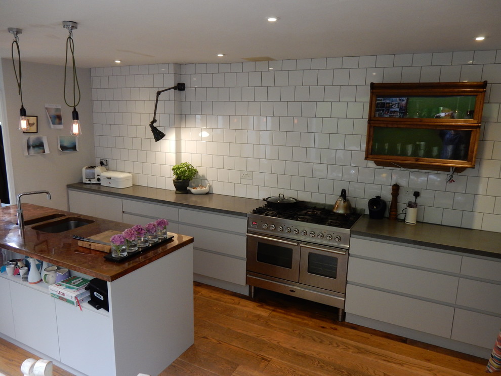 ウィルトシャーにある低価格の小さなインダストリアルスタイルのおしゃれなキッチン (フラットパネル扉のキャビネット、グレーのキャビネット、コンクリートカウンター、白いキッチンパネル、セラミックタイルのキッチンパネル、シルバーの調理設備) の写真