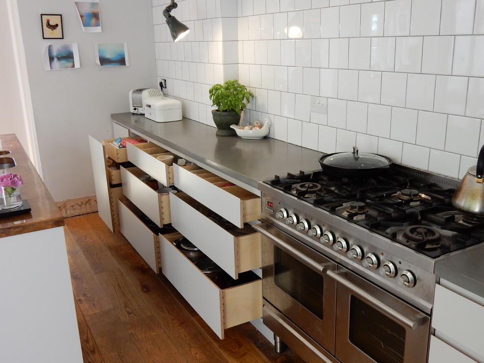 Small urban galley eat-in kitchen photo in Wiltshire with flat-panel cabinets, gray cabinets, concrete countertops, white backsplash, ceramic backsplash and stainless steel appliances