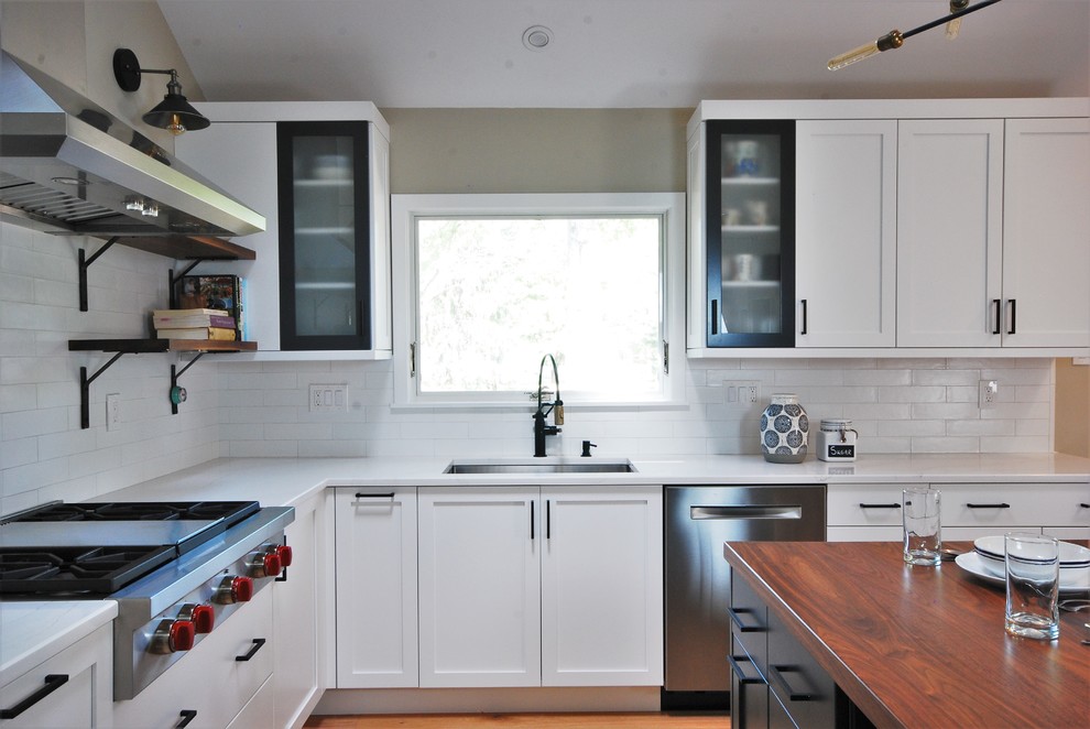 Foto på ett mellanstort industriellt vit kök, med en enkel diskho, skåp i shakerstil, vita skåp, bänkskiva i kvarts, vitt stänkskydd, stänkskydd i tunnelbanekakel, rostfria vitvaror och plywoodgolv