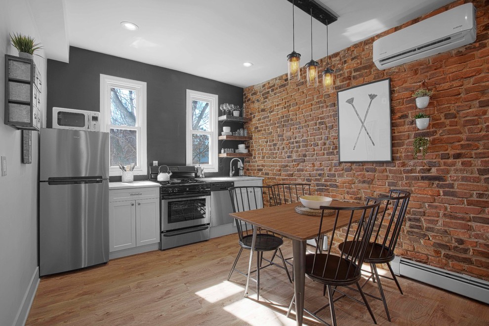 This is an example of an urban single-wall kitchen/diner in New York with a submerged sink, shaker cabinets, white cabinets, grey splashback, stainless steel appliances, medium hardwood flooring and no island.