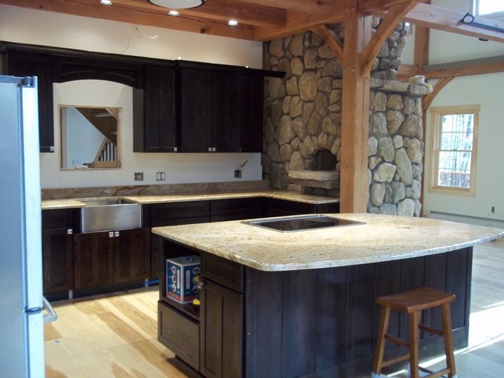 Example of a large u-shaped light wood floor eat-in kitchen design in Boston with a farmhouse sink, raised-panel cabinets, dark wood cabinets, granite countertops, white backsplash, ceramic backsplash, stainless steel appliances and no island