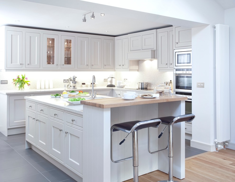 Ejemplo de cocina clásica renovada con armarios estilo shaker, puertas de armario blancas y electrodomésticos de acero inoxidable
