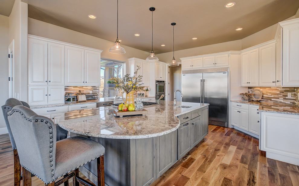 Large transitional u-shaped medium tone wood floor enclosed kitchen photo in Denver with an undermount sink, raised-panel cabinets, white cabinets, granite countertops, beige backsplash, matchstick tile backsplash, stainless steel appliances and an island