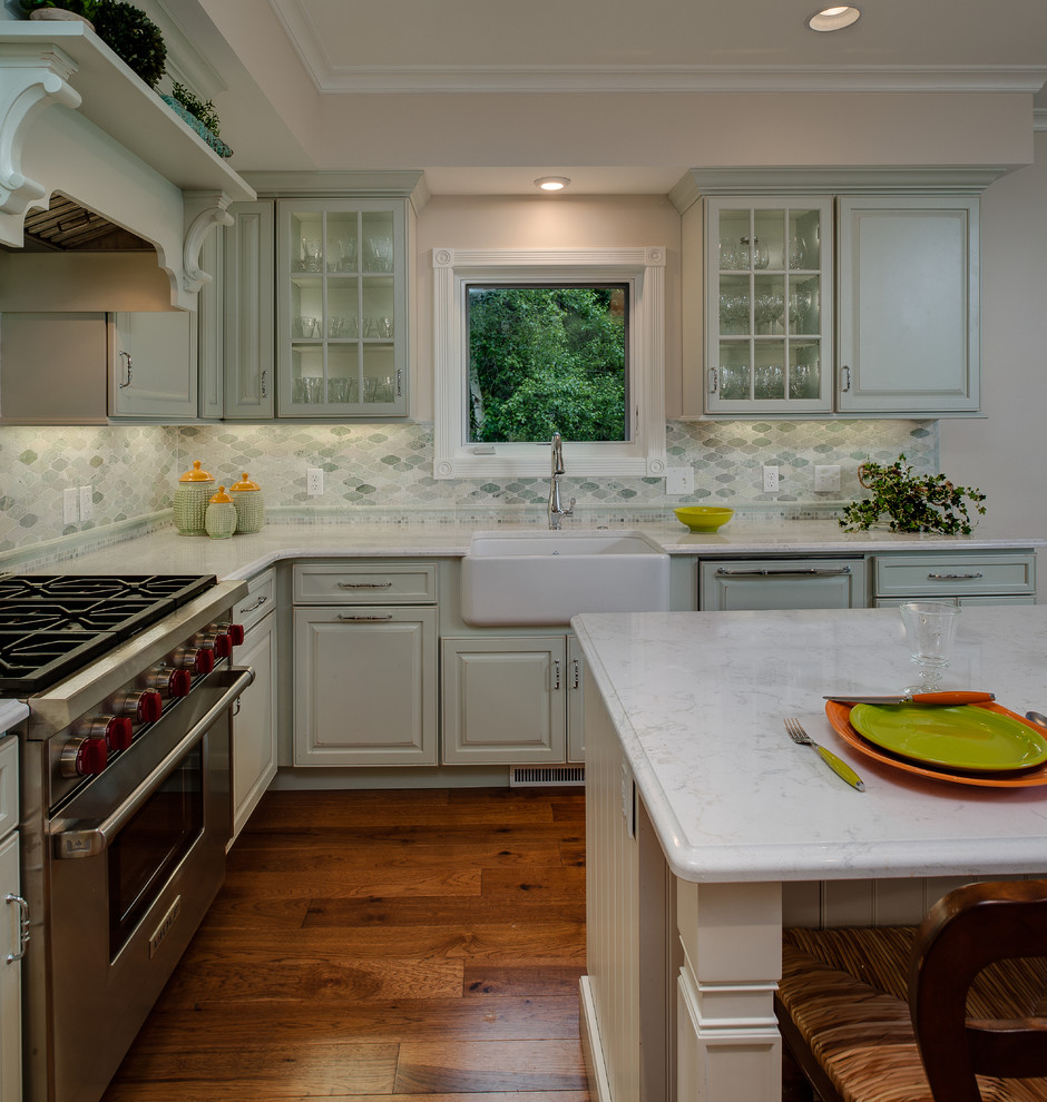 Exempel på ett mellanstort klassiskt kök, med en rustik diskho, luckor med upphöjd panel, gröna skåp, bänkskiva i kvarts, grönt stänkskydd, stänkskydd i mosaik, rostfria vitvaror, mellanmörkt trägolv, en köksö och brunt golv