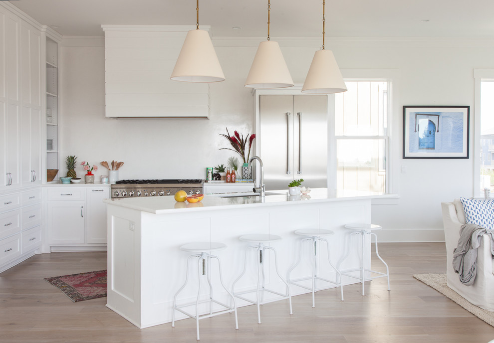 Foto di una cucina stile marinaro con ante bianche, paraspruzzi bianco, elettrodomestici in acciaio inossidabile e parquet chiaro