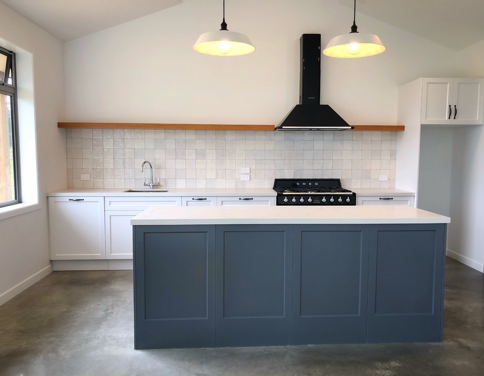 Exempel på ett stort industriellt grå linjärt grått kök och matrum, med skåp i shakerstil, vita skåp, vitt stänkskydd, stänkskydd i keramik, betonggolv, en köksö och grått golv