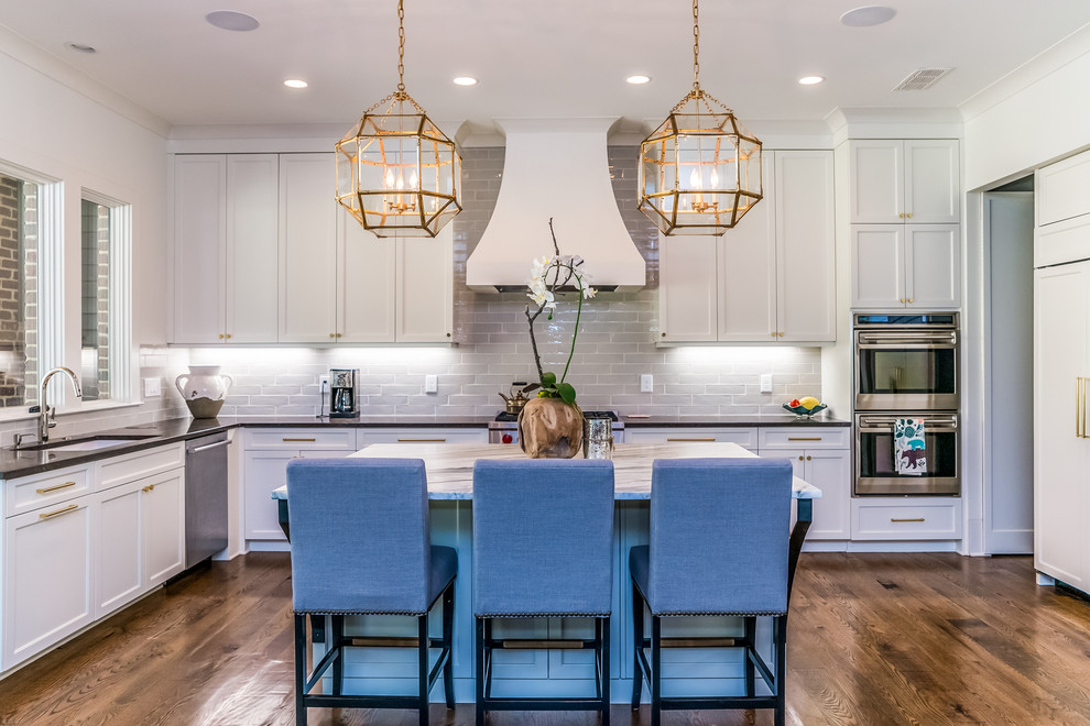 Design ideas for a classic l-shaped kitchen in Atlanta with shaker cabinets, white cabinets, grey splashback, stainless steel appliances, dark hardwood flooring, an island and brown floors.