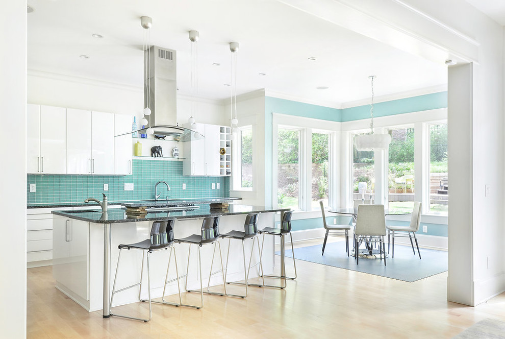 Immagine di una cucina minimal con lavello sottopiano, ante lisce, ante bianche, top in granito, paraspruzzi blu, paraspruzzi con piastrelle di vetro, elettrodomestici in acciaio inossidabile e parquet chiaro