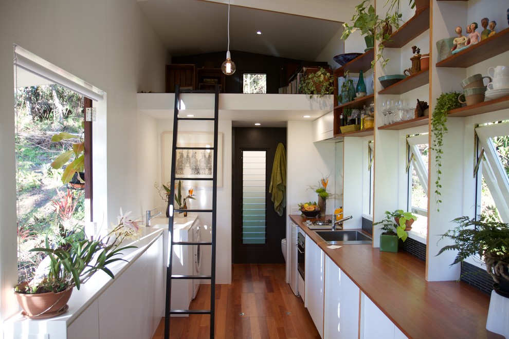 Immagine di una piccola cucina design con lavello da incasso, ante bianche, top in legno e pavimento in legno massello medio