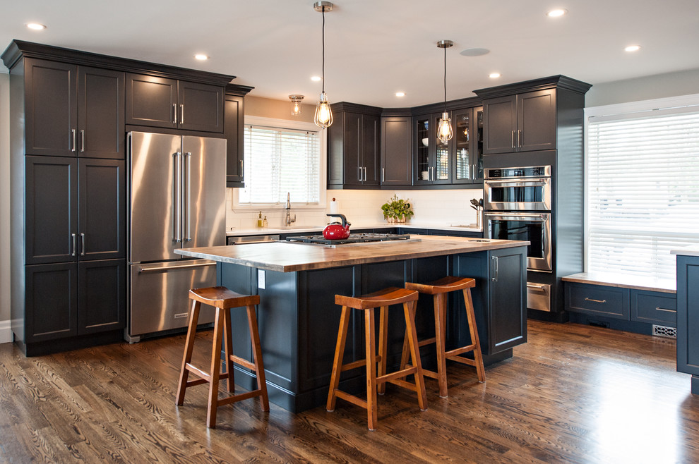 Inspiration for a mid-sized modern l-shaped medium tone wood floor eat-in kitchen remodel with an undermount sink, shaker cabinets, blue cabinets, granite countertops, white backsplash, subway tile backsplash, stainless steel appliances and an island