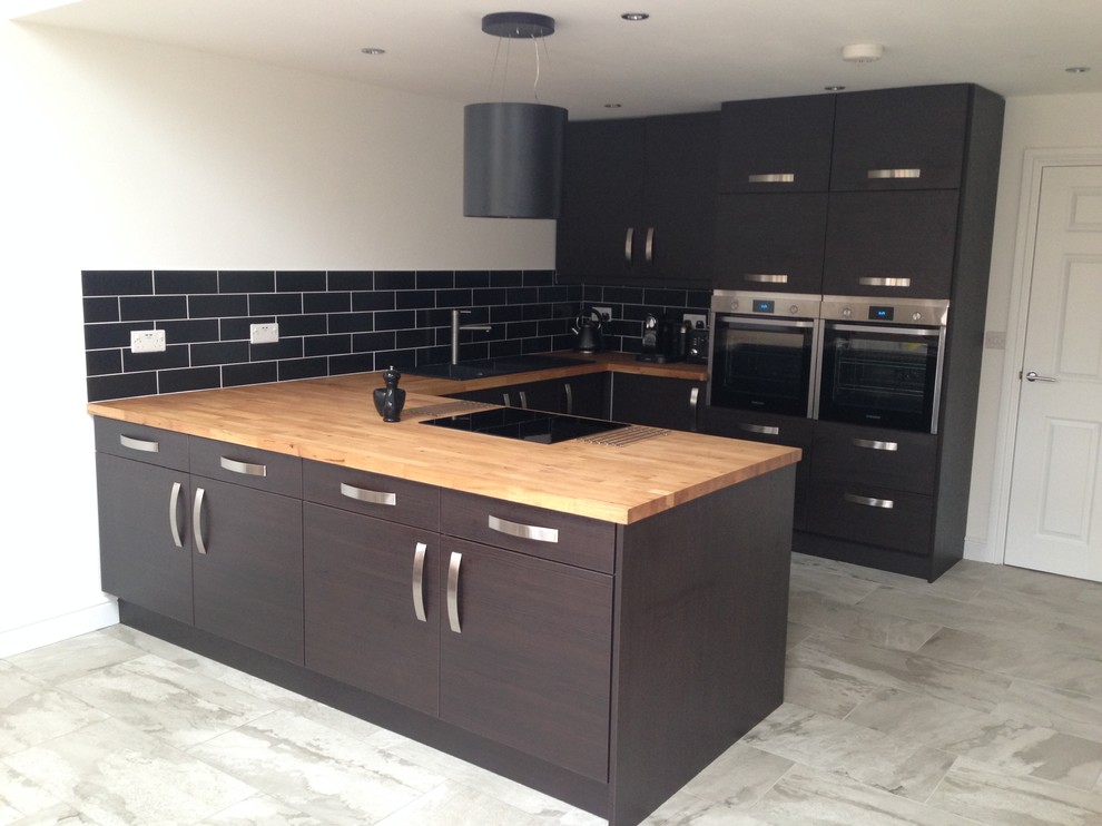 Inspiration for a medium sized u-shaped kitchen/diner in Cambridgeshire with flat-panel cabinets, brown cabinets, wood worktops and a breakfast bar.