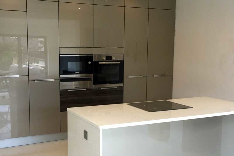 Imagen de cocina comedor lineal contemporánea pequeña con armarios con paneles lisos, puertas de armario beige, encimera de cuarcita, electrodomésticos negros y una isla