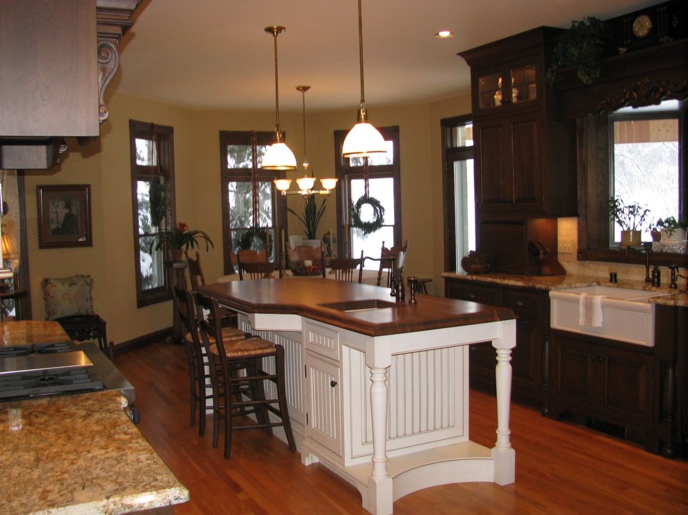Bild på ett stort lantligt kök, med en rustik diskho, luckor med profilerade fronter, beige skåp, granitbänkskiva, rostfria vitvaror, ljust trägolv, en köksö, beige stänkskydd och brunt golv