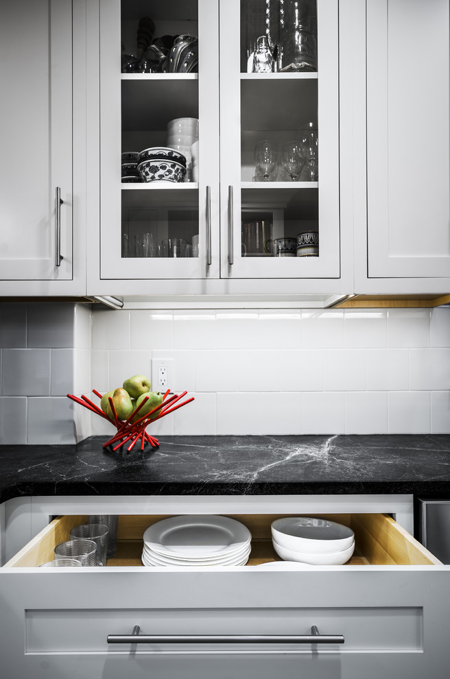 Exempel på ett litet klassiskt kök, med en undermonterad diskho, luckor med profilerade fronter, vita skåp, bänkskiva i täljsten, vitt stänkskydd, stänkskydd i glaskakel, rostfria vitvaror, klinkergolv i porslin och en halv köksö