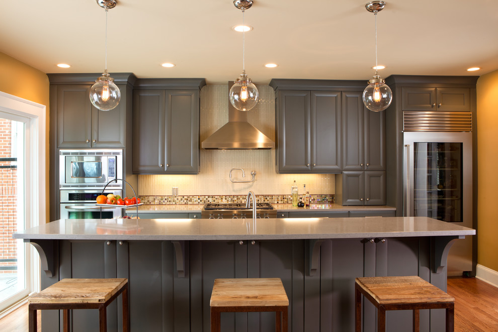 Kitchen - mid-sized traditional single-wall light wood floor kitchen idea in Atlanta with stainless steel appliances, recessed-panel cabinets, gray cabinets, quartz countertops, white backsplash, glass tile backsplash and an island