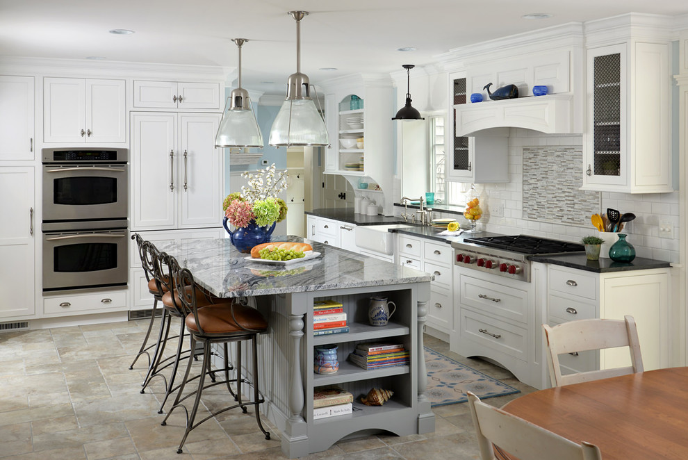 Exempel på ett avskilt, mellanstort klassiskt grå grått l-kök, med en rustik diskho, skåp i shakerstil, vita skåp, granitbänkskiva, vitt stänkskydd, stänkskydd i tunnelbanekakel, integrerade vitvaror, klinkergolv i porslin, en köksö och beiget golv
