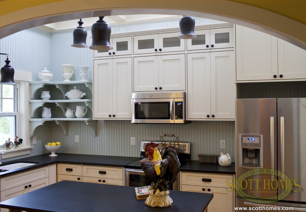 Inredning av ett klassiskt mellanstort kök, med en dubbel diskho, luckor med infälld panel, vita skåp, granitbänkskiva, vita vitvaror och mellanmörkt trägolv