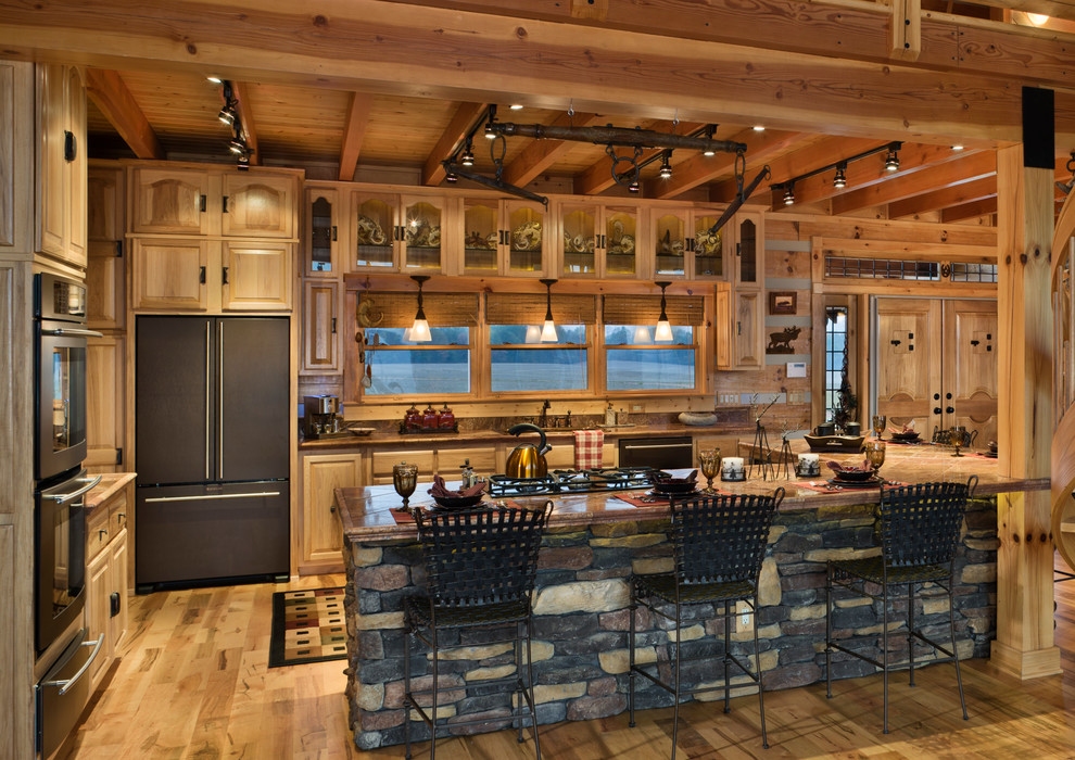 Photo of a large rustic l-shaped kitchen/diner in Louisville with a submerged sink, medium wood cabinets, black appliances, medium hardwood flooring and an island.
