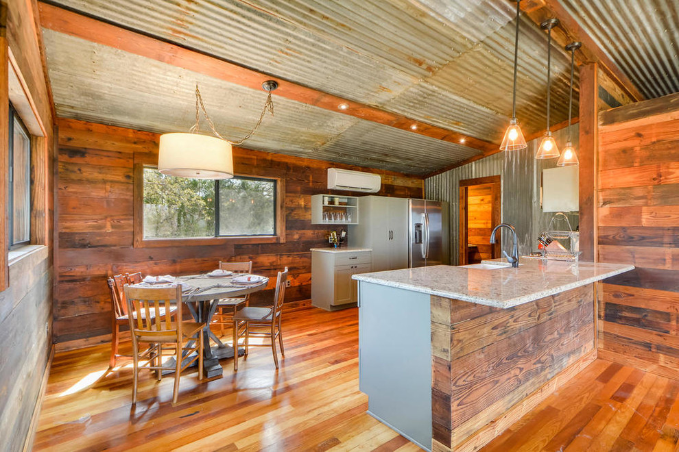 Rustikale Küche mit Landhausspüle, Schrankfronten im Shaker-Stil, grauen Schränken, Küchengeräten aus Edelstahl, braunem Holzboden und Halbinsel in Austin