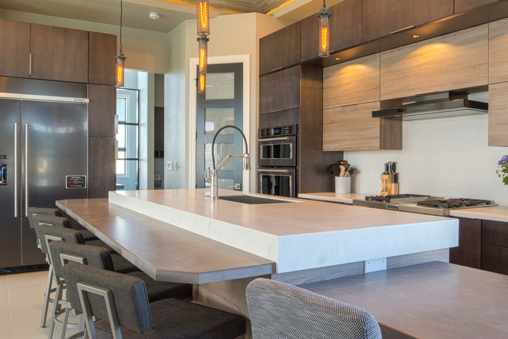 Example of a large minimalist l-shaped porcelain tile and beige floor open concept kitchen design in Other with flat-panel cabinets, stainless steel appliances, an island, an undermount sink, light wood cabinets and marble countertops