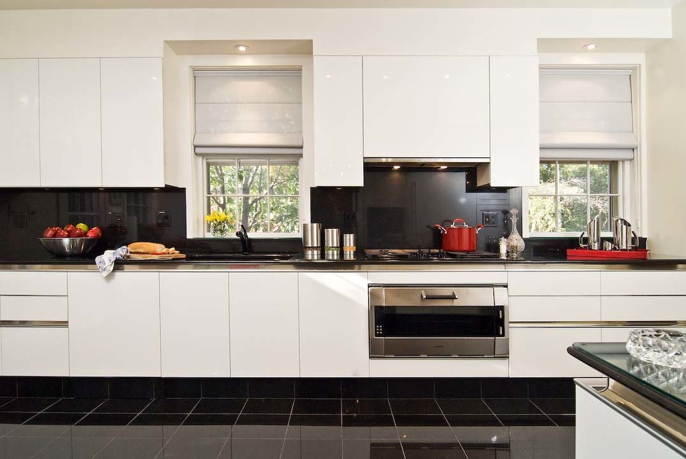 Immagine di una cucina design con ante lisce, ante bianche, elettrodomestici in acciaio inossidabile e paraspruzzi nero