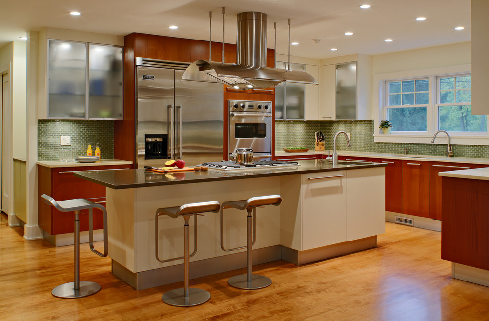 Cette image montre une cuisine minimaliste en bois foncé avec un placard à porte plane, une crédence verte et un électroménager en acier inoxydable.