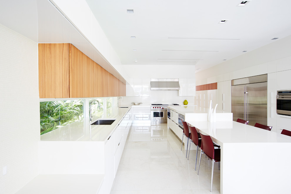 Moderne Wohnküche in U-Form mit Unterbauwaschbecken, flächenbündigen Schrankfronten, weißen Schränken, Küchengeräten aus Edelstahl und Kücheninsel in Miami